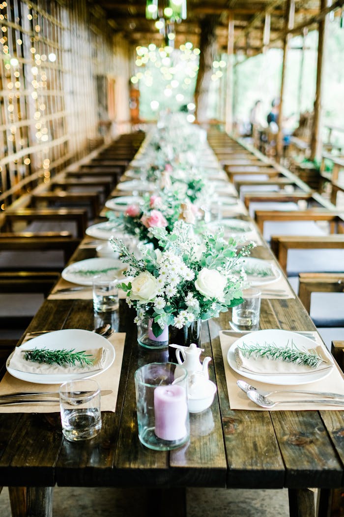 A beautifully decorated rustic table setting featuring floral arrangements, candles, and fine cutlery.